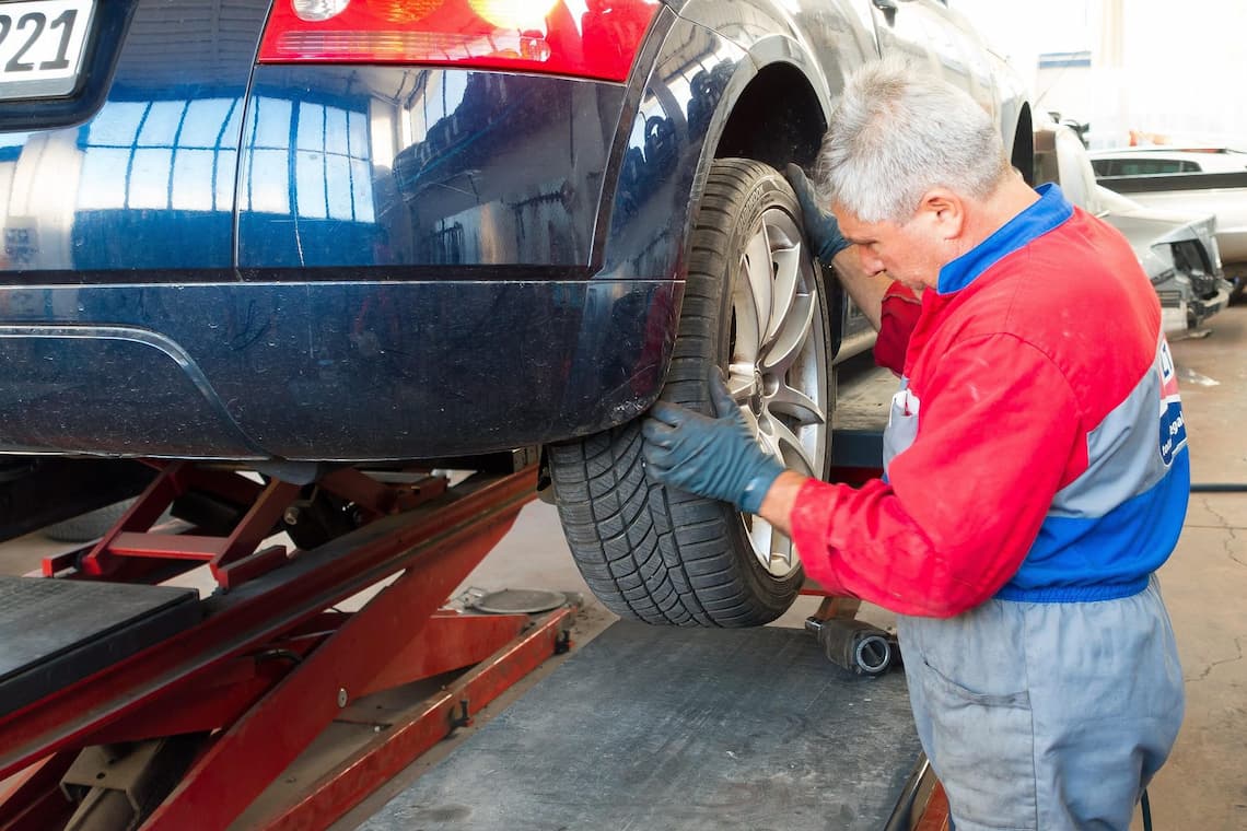 auto repair shop mechanic adjusting tire — reduce Tekmetric payment processing fees for auto shops
