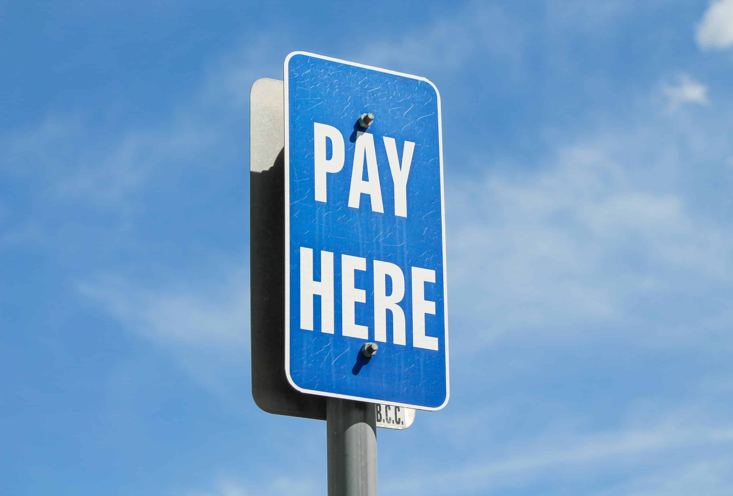 Pay here sign representing the merchant services early termination fee decision every switching merchant faces