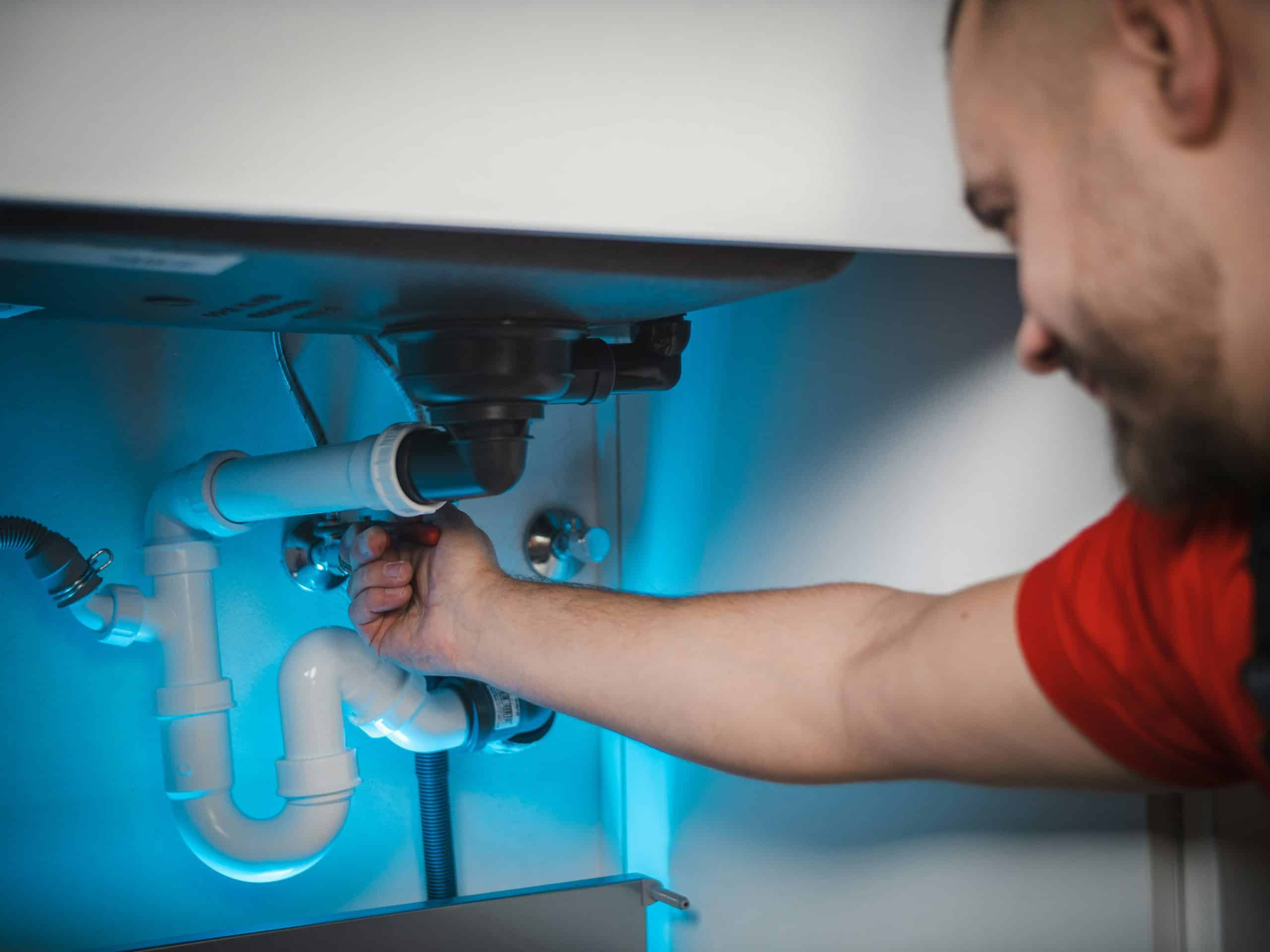 reduce Jobber payment processing fees — plumber working under sink pipes