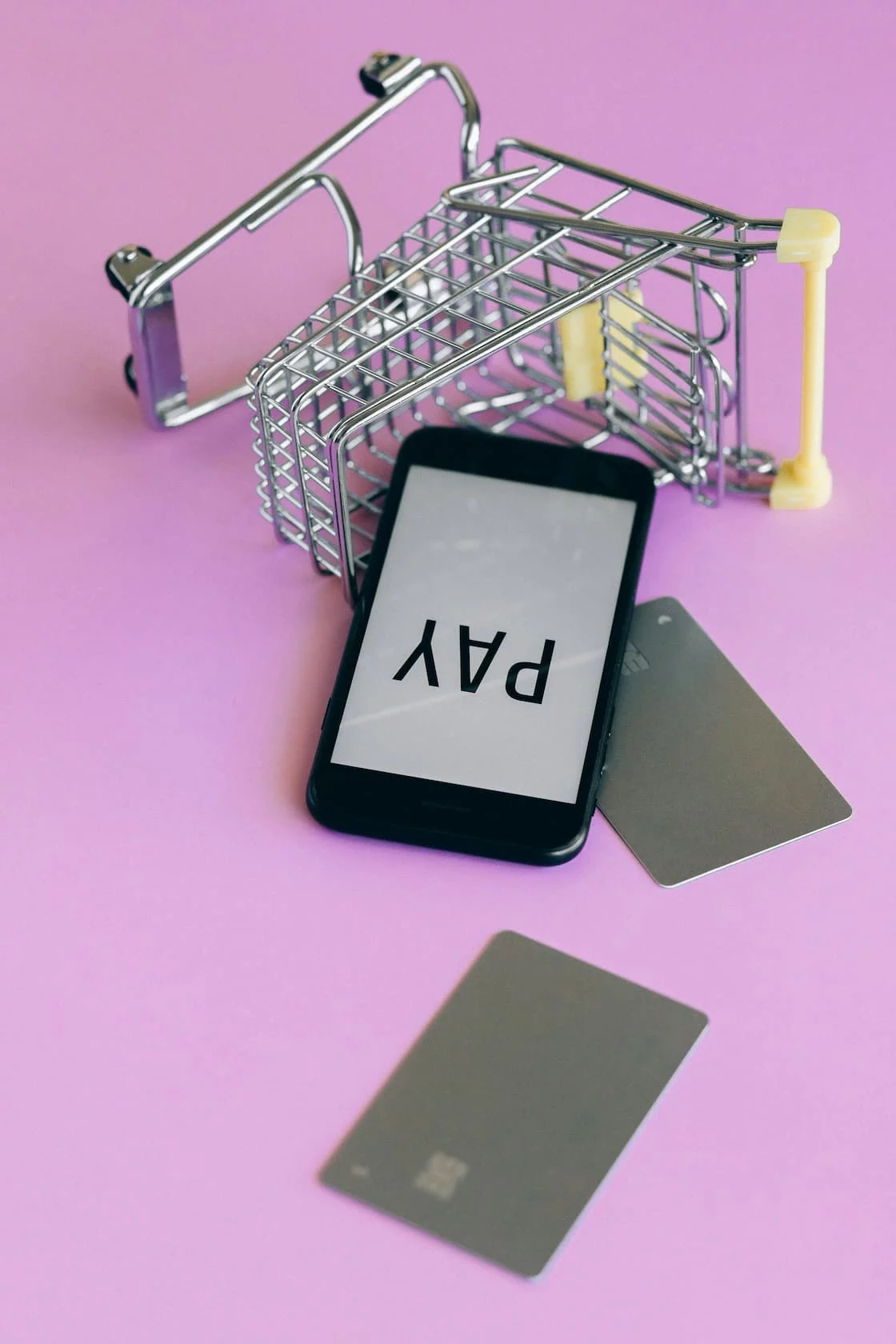 A smartphone showing a pay screen beside a card and a shopping cart, representing buy now pay later at checkout