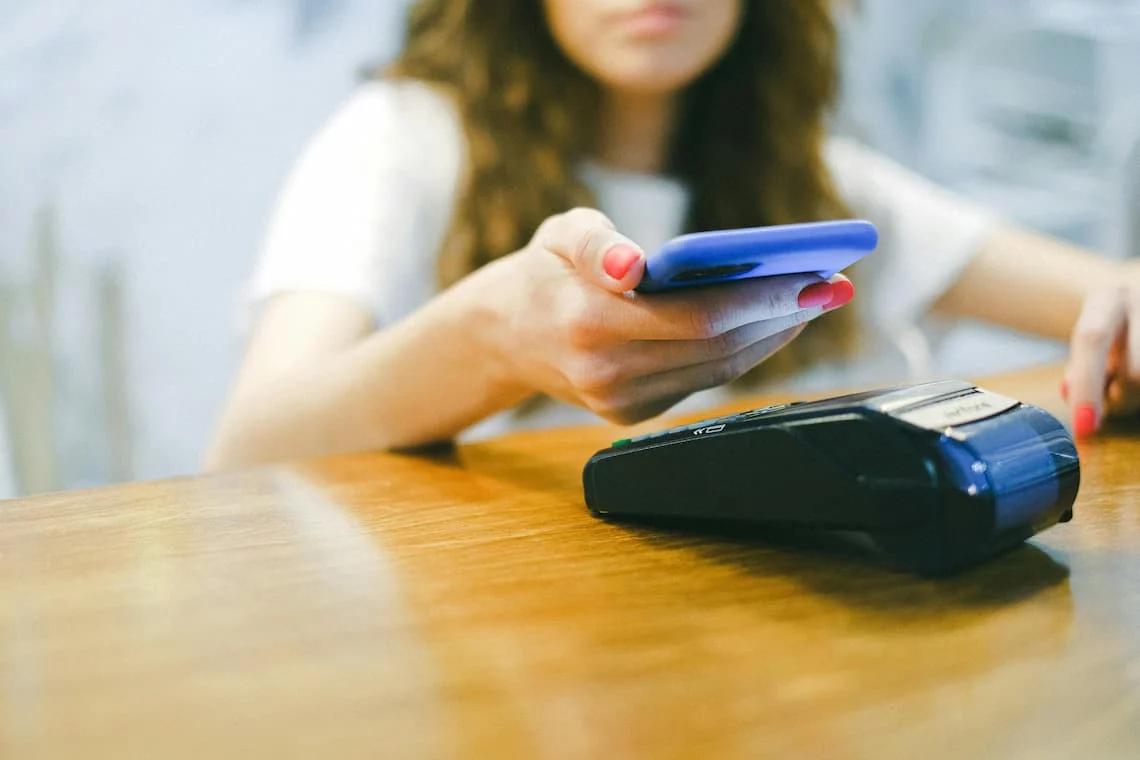 A contactless card tapping a smartphone using tap to pay, with the phone acting as the payment terminal