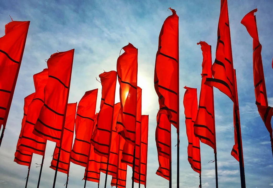 a field of red warning flags against the sky representing merchant agreement red flags to spot before signing