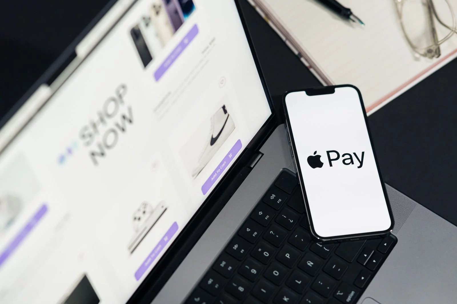 Apple Pay on a phone beside a laptop store — how to accept digital wallets as a merchant